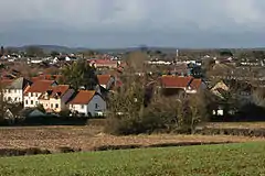 Multiple reddish brown roofs of houses. A church tower is visible in the distance.