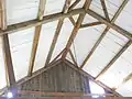 Common purlin framing with vertical boards in New England. This method of framing may be descended from board roofs but does not mean the roofing was originally just the boards.