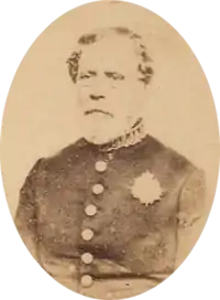 Sepia toned tintype photograph half-length portrait of an older, bearded man wearing a simple military frock coat with large buttons and a single medal over the left breast