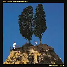 Two trees on a hill surrounded by blue sky. Two men in white and two men in black stand on the hill.