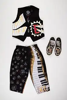 Laid flat on a white background is a waistcoat, trousers and shoes. All with decorative elements - stylized keyboards, patterns and a funky hand-drawn E with a triangle border on the waistcoat.