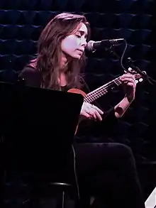 Milioti strumming a ukulele onstage