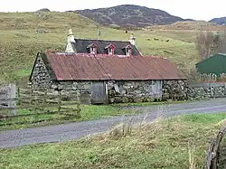 Croft in Upper Ardelve, a Highland settlement on Loch Alsh (2007). Image shows farmhouse behind a modest livestock shed. Cows graze the rear fields.