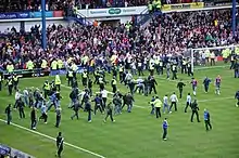 A large number of spectators running onto the field