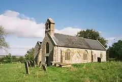 Stone building with arched windows. In the foreground are gravestones.