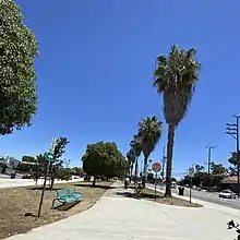 Bike path westernmost point with signage, bench and palm trees