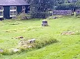 Footings of south transept and base of a column. The shed in the background is the museum, on the site of the chapter house.