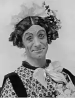 Head and shoulder photo of a man in frilly women's clothing, smiling at the viewer