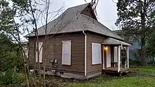 A small, brown house with wood siding and a steep roof.