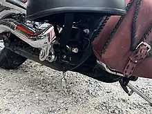 A silver bell hanging below a motorcycle.