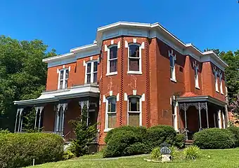 North Danville Italianate style home. This two-story brick dwelling has an original veranda, a two-story bay, arched windows with keystones, and rectangular wood panels at the cornice.