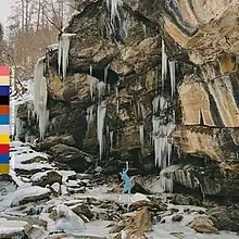 Richard standing by a rock formation with a thin bar to the side made up of several colors