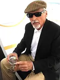 Dennis Hopper, with gray hair and a gray goatee, wearing a hat and sunglasses