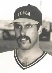 A baseball player in a white jersey and dark cap