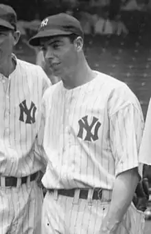 A man in a light baseball uniform with dark pinstripes and dark cap