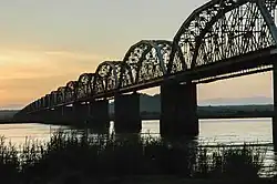 A long railway bridge backlit by the setting sun