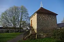 Photo of old dovecote, boxes converted to windows, sharp spike on top, and modern concrete stairs added externally