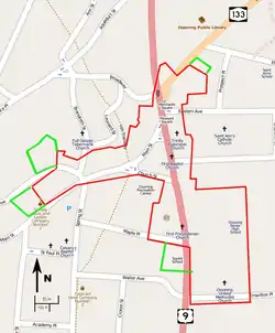 A map of the streets in downtown Ossining, on a gray background with major roads in pink and orange and the locations of some landmarks indicated. The border of the irregularly-shaped historic district is in red. Four small green-bordered areas are adjacent to it.