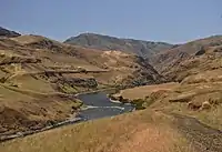 Narrow river turning between brown hills