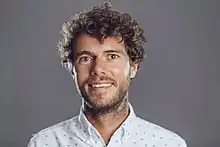 A white man in his 20s or 30s, with brown hair, smiling at the camera.