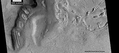 Dipping layers, as seen by HiRISE under HiWish program Also, Ribbed Upper plains material is visible in the upper right of the picture.  It is forming from the upper plains unit, and in turn is being eroded into brain terrain.