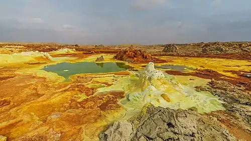 Image 4DallolPhotograph credit: Alexander SavinDallol is a cinder-cone volcano in the Danakil Depression, northeast of the Erta Ale Range in Ethiopia. The area lies up to 120 m (390 ft) below sea level, and has been repeatedly flooded in the past when waters from the Red Sea have inundated it. The Danakil Depression is one of the hottest places on Earth, and the evaporation of seawater after these flooding episodes produced thick deposits of salt, as seen in this landscape. The deposits at Dallol include significant quantities of the carbonate, sulfate and chloride salts of sodium, potassium, calcium and magnesium. Hot springs discharge brine to form the blueish ponds, and small, temporary geysers produce cones of salt.More selected pictures