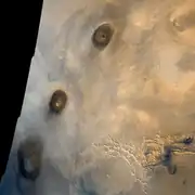 Three volcanoes comprise the Tharsis Montes: Arsia Mons (in the south), Pavonis Mons (at center) and Ascraeus Mons (in the north). Image mosaic is from Viking 1 Orbiter (1980).