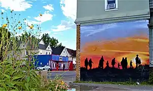 A mural on Dewey Avenue depicting migrants seeking out a new home.