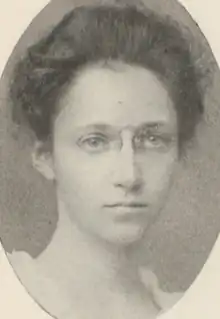 A young white woman, dark hair dressed in a bouffant updo, wearing pince-nez glasses, in an oval frame