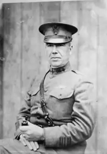 A man in military uniform, wearing a peaked cap, sitting facing slightly to the left