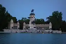 A colonnade by the pond around an equestrian statue.