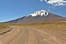 A snow-covered, barren mountain rising from a road