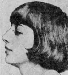 A young white woman with bobbed dark hair cut in bangs, photographed in profile