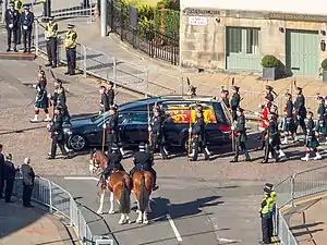 An image of a hearse with a coffin inside, draped with a Royal Standard