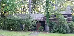 Photo of a home with unpainted redwood siding sitting among trees.