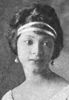 A young light-skinned African-American woman, with bouffant styled hair and a double ribbon headband across her forehead; she is wearing drop earrings and a scoop-necked dress or blouse