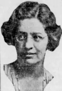 A newspaper photo of a white woman with bobbed wavy hair, wearing eyeglasses