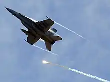 Bottom view of jet fighter in-flight releasing bright orange flares