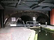 Farmer's Bridge Lock 9 and extended pound, running through two arches of the Newhall Street bridge in central Birmingham. There is a lock gate on either side of the road.