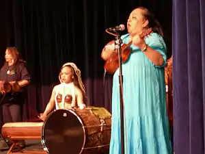 Hawaiian musicians wearing traditional dress, including a muumuu