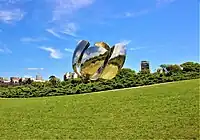 The metal sculpture has six petals curved inwards pointing up and to the side with four stamen in the middle