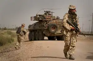 Australian soldiers supported by an ASLAV-25 patrol along a railway line near Camp Smitty during routine foot patrols in Al Muthanna Province