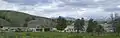 alt=Photograph of Fort Yellowstone, showing several Army buildings, modern motor vehicles, and the wide-open Yellowstone landscape in the background.