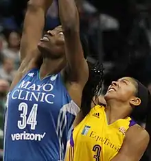 Two very tall women, Fowles at left straining for the ball, Parker beneath her, also straining