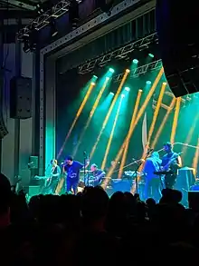 Portrait photo of Foxing (band), performing live in concert, at Roxian Theatre, in Pittsburgh, Pennsylvania. Photo shows members of the band on stage with audience in foreground.