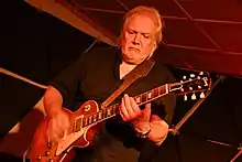 Luboš Andršt performing onstage, looking intently at his guitar