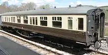 A long coach with domed roof ends. The roof is pale grey and ends black. The body has brown lower parts but cream above around the windows.