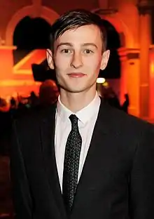 A dark-haired man wearing suit and tie poses for the camera