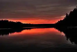 Wooded banks of the lake silhouetted against deep red sky