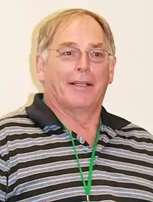 A blonde-haired man with glasses and a striped shirt